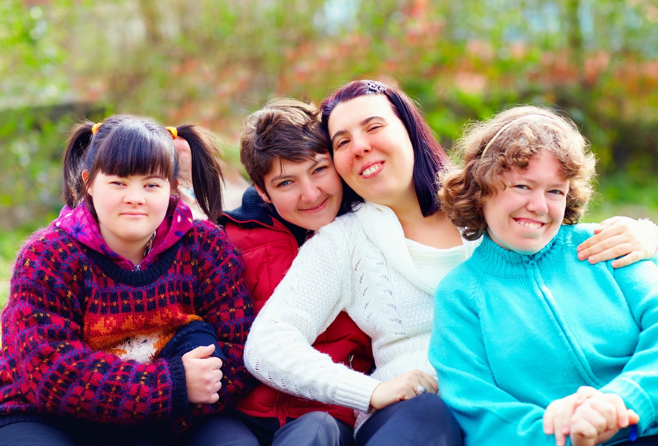 Group of young people with intellectual disabilities smiling together outdoors, representing NDIS participants