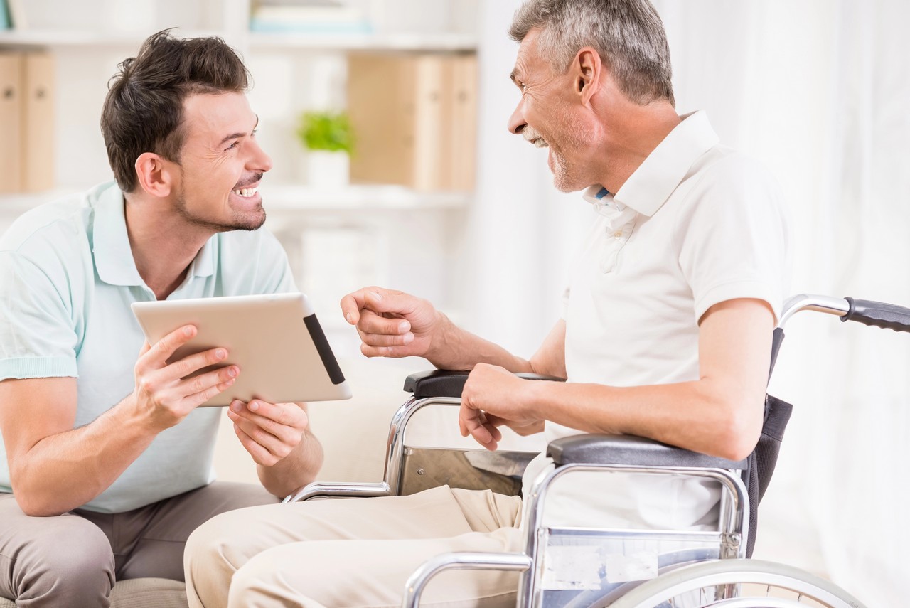 Support worker discussing care options with a man in a wheelchair using a digital tablet