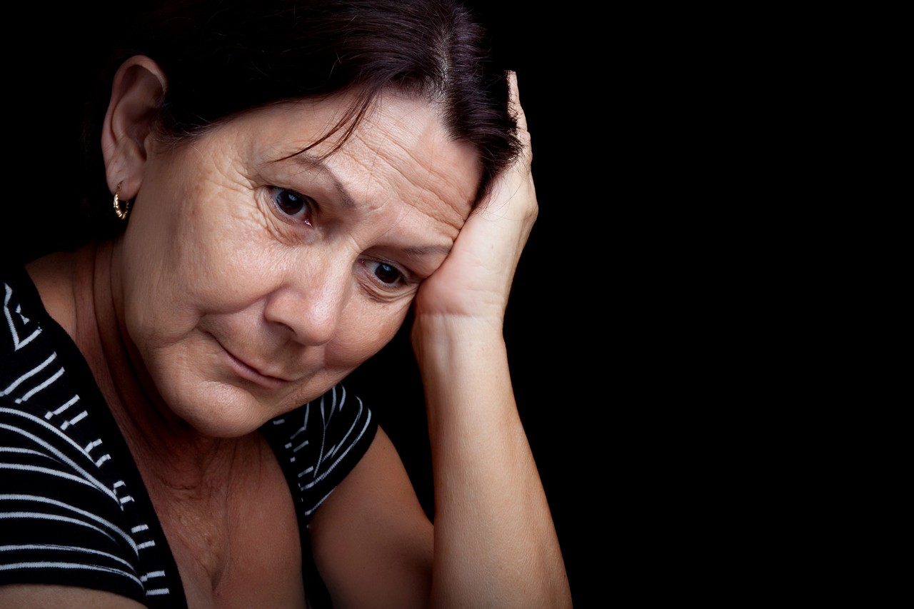Woman resting her head on her hand looking distressed, illustrating the impact of mental health challenges in the workplace
